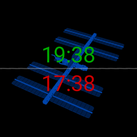 Zulu Face con una silueta azul de la Estación Espacial Internacional detrás de las horas: hora local 19:38 en verde arriba, hora Zulú/UTC 17:38 en rojo abajo, sobre negro.